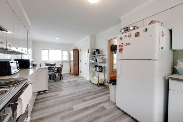 kitchen with white cabinets, white refrigerator, crown molding, and light hardwood / wood-style flooring