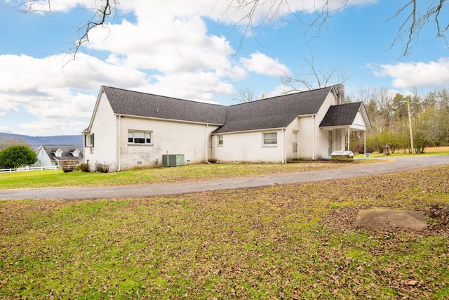 view of property exterior with a lawn and cooling unit