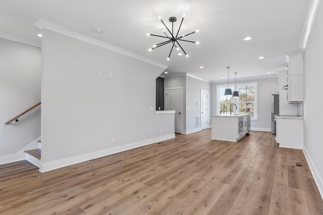 unfurnished living room featuring crown molding, sink, light hardwood / wood-style floors, and an inviting chandelier