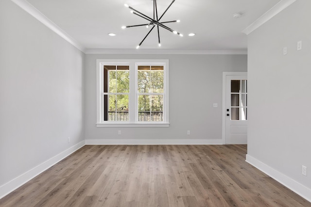 empty room featuring light hardwood / wood-style flooring, crown molding, and a notable chandelier