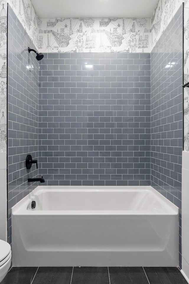 bathroom featuring tile patterned floors, toilet, and washtub / shower combination