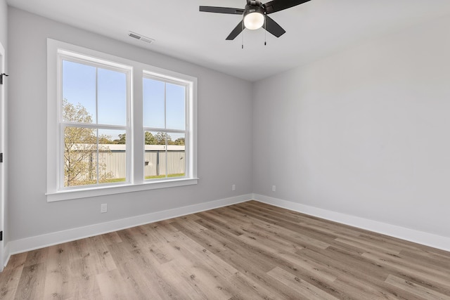 empty room with a wealth of natural light, ceiling fan, and light hardwood / wood-style floors