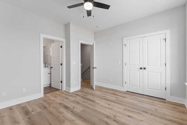 unfurnished bedroom with sink, ceiling fan, light wood-type flooring, connected bathroom, and a closet