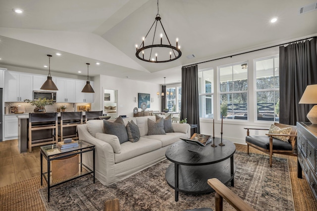 living room featuring dark hardwood / wood-style floors, vaulted ceiling, and an inviting chandelier