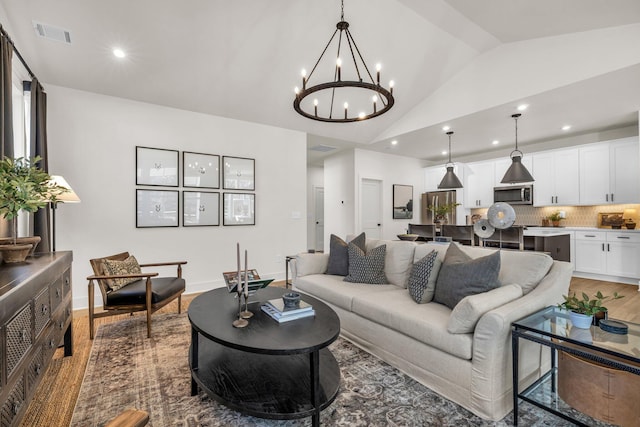 living room featuring hardwood / wood-style flooring, a notable chandelier, and vaulted ceiling