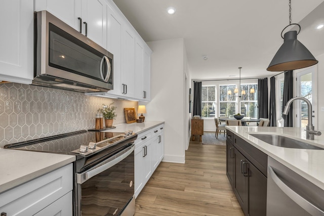 kitchen with white cabinets, appliances with stainless steel finishes, hanging light fixtures, and sink