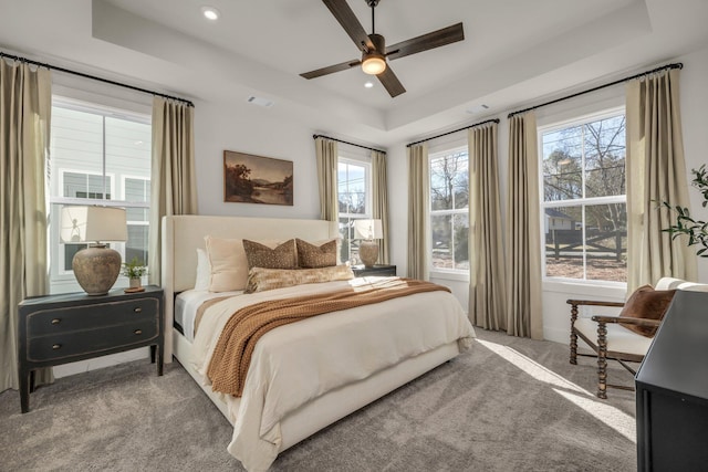 bedroom with a tray ceiling, ceiling fan, and carpet flooring