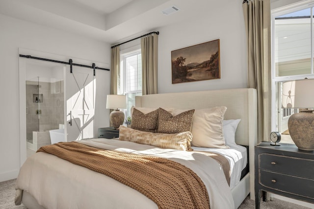 carpeted bedroom featuring a barn door and ensuite bathroom