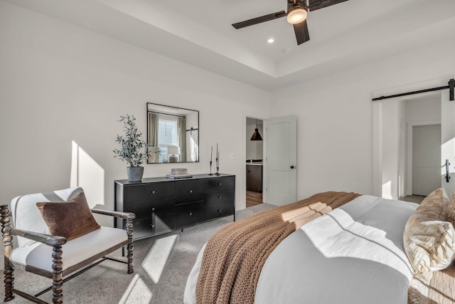 carpeted bedroom with a barn door and ceiling fan