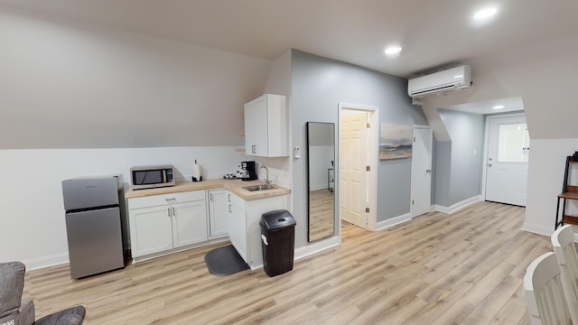 kitchen with stainless steel appliances, a wall mounted AC, light hardwood / wood-style flooring, white cabinets, and butcher block counters