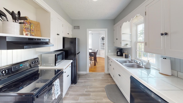 kitchen featuring exhaust hood, black appliances, white cabinets, sink, and a textured ceiling