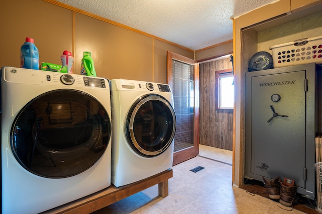 laundry area with a textured ceiling, washer and clothes dryer, and wooden walls