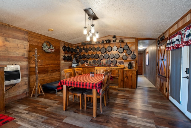 dining space featuring wooden walls, vaulted ceiling, a textured ceiling, dark hardwood / wood-style flooring, and heating unit