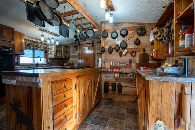 kitchen with a textured ceiling, double oven, stainless steel gas cooktop, and sink