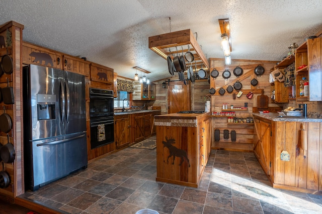 kitchen with wood walls, sink, a textured ceiling, appliances with stainless steel finishes, and kitchen peninsula