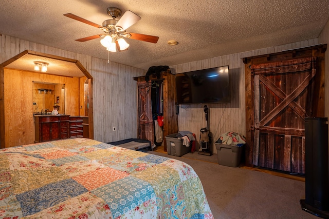 carpeted bedroom with a textured ceiling, ceiling fan, and wooden walls