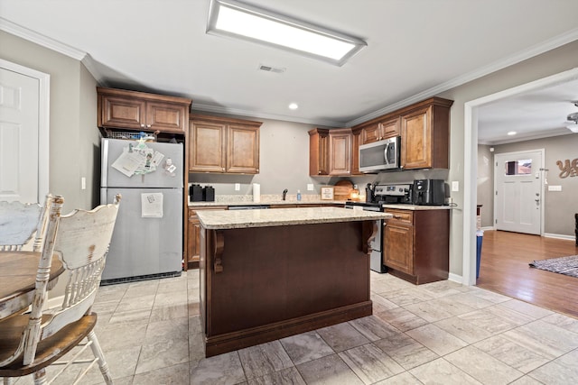 kitchen with visible vents, a kitchen island, appliances with stainless steel finishes, and ornamental molding