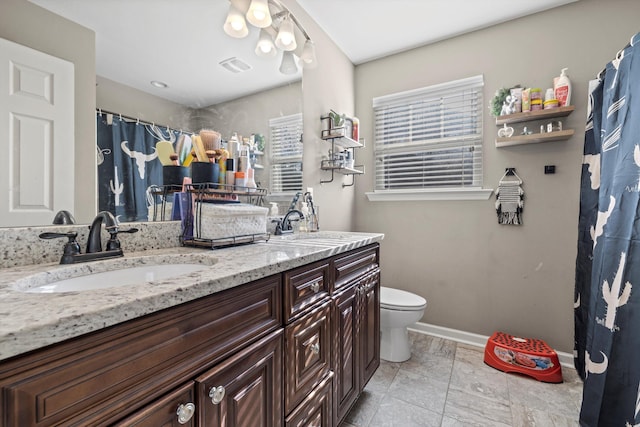 full bath with double vanity, a sink, toilet, and baseboards