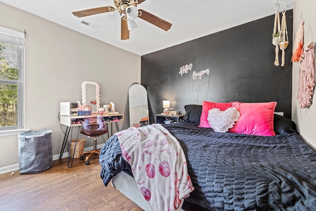 bedroom featuring multiple windows, wood finished floors, visible vents, and baseboards