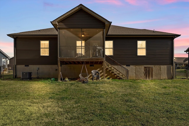 back of property with a sunroom, a yard, stairway, and crawl space