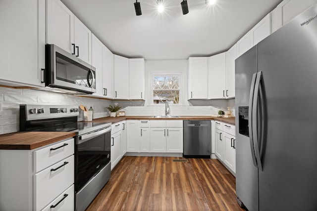 kitchen featuring wooden counters, sink, dark hardwood / wood-style flooring, white cabinetry, and stainless steel appliances