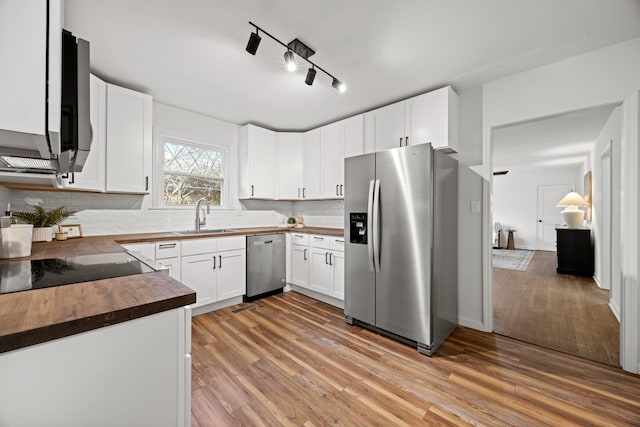 kitchen featuring wooden counters, appliances with stainless steel finishes, sink, white cabinets, and light hardwood / wood-style floors