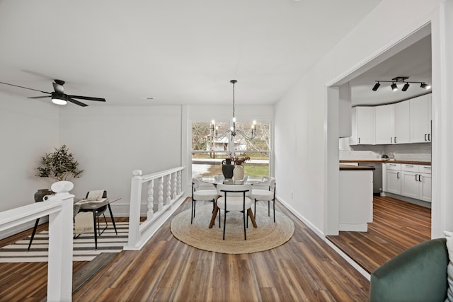 dining room with ceiling fan with notable chandelier and dark hardwood / wood-style flooring