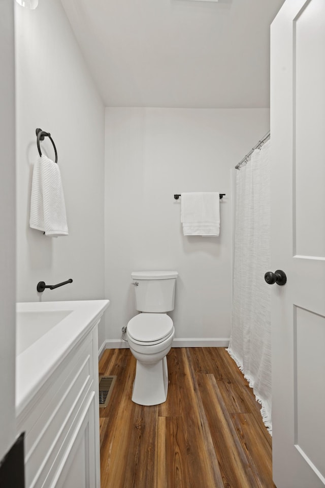 bathroom with wood-type flooring, vanity, and toilet