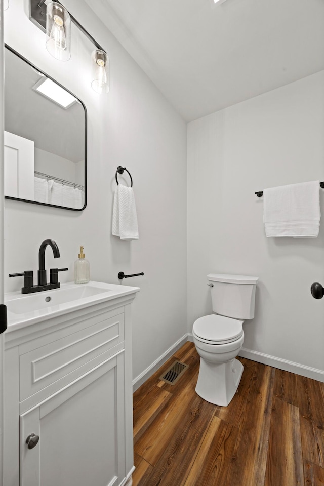 bathroom with toilet, vanity, and hardwood / wood-style flooring