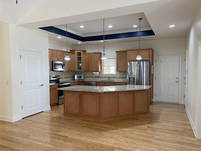 kitchen featuring hanging light fixtures, stainless steel appliances, sink, and a tray ceiling