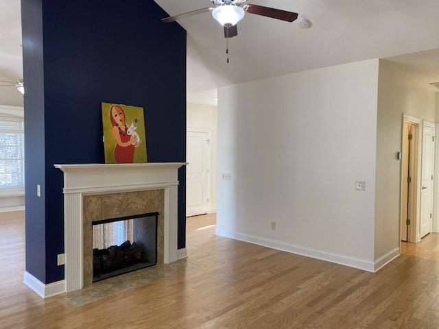 unfurnished living room featuring a tile fireplace, light wood-type flooring, and ceiling fan