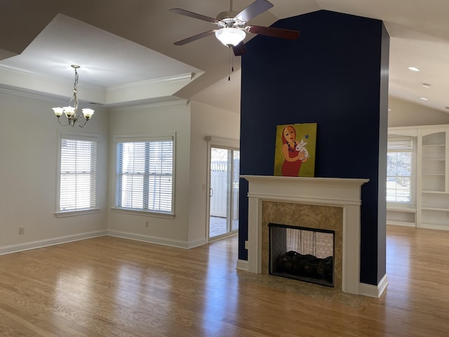 unfurnished living room featuring a tile fireplace, light wood-type flooring, built in shelves, and plenty of natural light