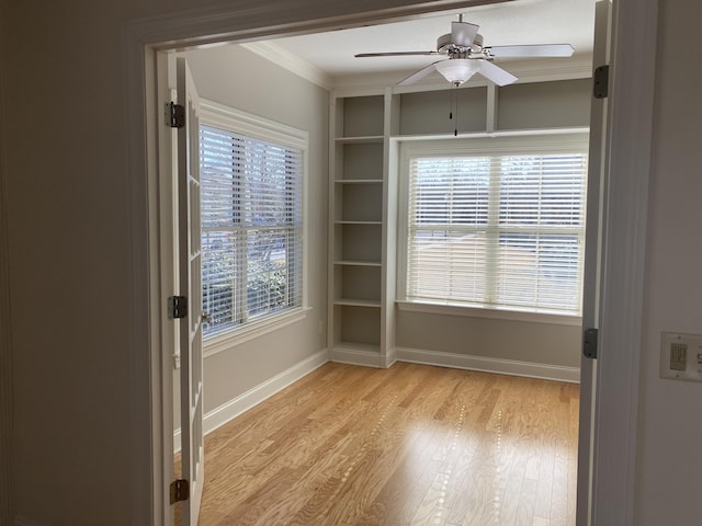 empty room with ceiling fan, light wood-type flooring, and crown molding