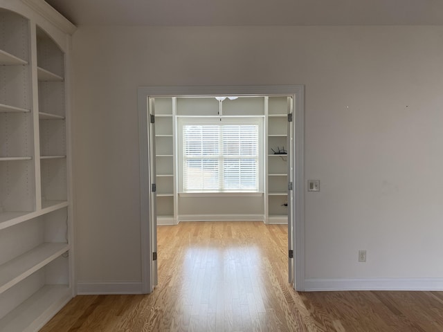 spare room featuring light wood-type flooring and built in shelves