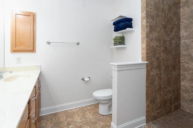 bathroom with toilet, vanity, tile patterned flooring, and tiled shower