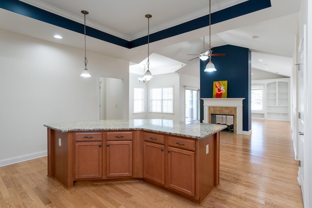 kitchen featuring light stone countertops, a kitchen island, pendant lighting, and light hardwood / wood-style flooring