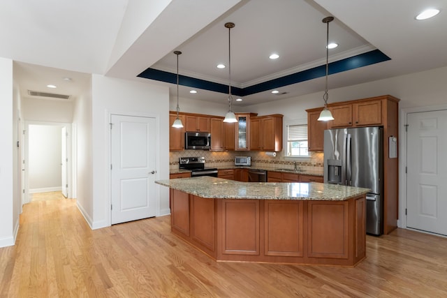 kitchen featuring light stone countertops, a raised ceiling, decorative light fixtures, and appliances with stainless steel finishes