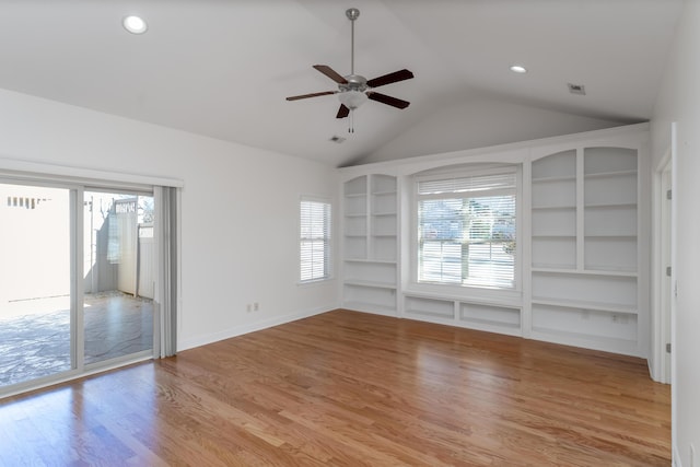 empty room featuring vaulted ceiling, built in features, ceiling fan, and light hardwood / wood-style flooring