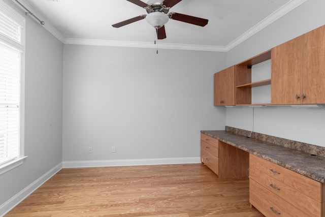 unfurnished office featuring built in desk, ceiling fan, crown molding, and light hardwood / wood-style flooring