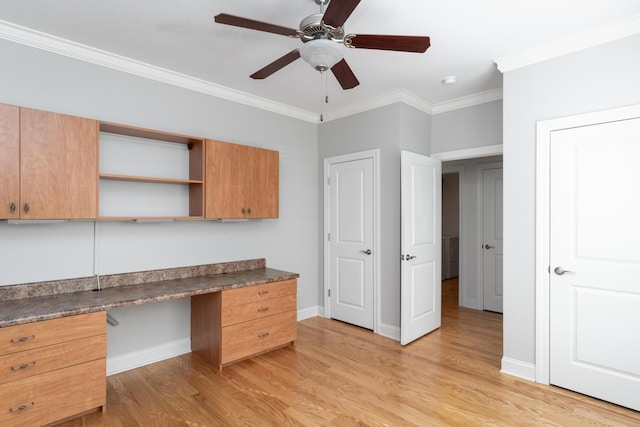 unfurnished office featuring built in desk, ceiling fan, light hardwood / wood-style flooring, and crown molding