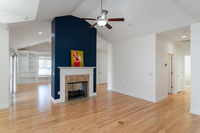 living room featuring ceiling fan, a premium fireplace, built in features, and light wood-type flooring