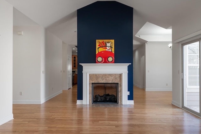 unfurnished living room featuring a tile fireplace, light wood-type flooring, and ornamental molding