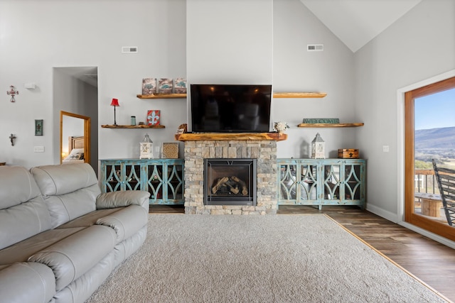 living room featuring high vaulted ceiling, dark wood-type flooring, and a stone fireplace