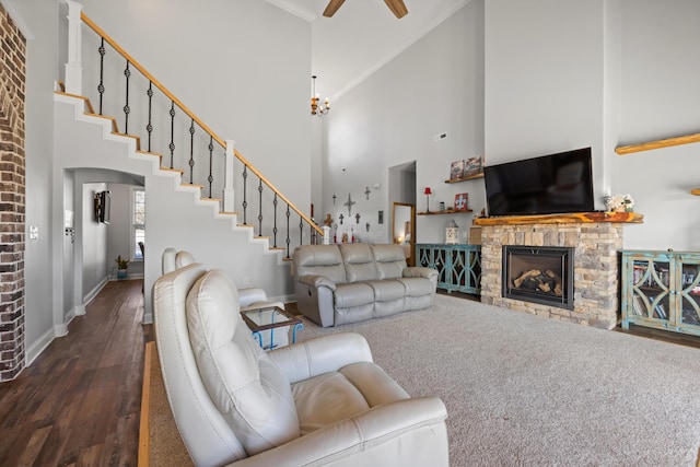 living room featuring a towering ceiling, ceiling fan, dark hardwood / wood-style floors, and a stone fireplace