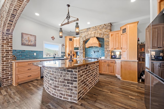 kitchen with custom exhaust hood, light brown cabinetry, tasteful backsplash, and a kitchen island