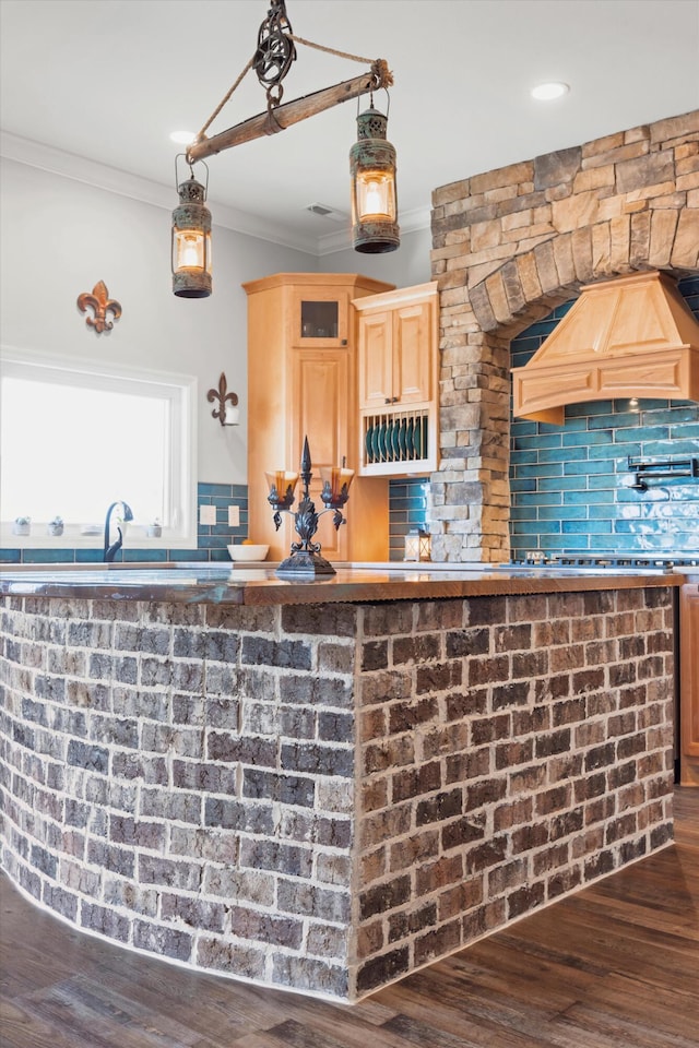 interior space with tasteful backsplash, decorative light fixtures, crown molding, light brown cabinets, and dark hardwood / wood-style flooring