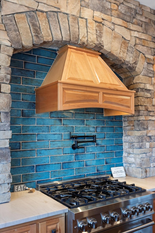 kitchen with stainless steel range, tasteful backsplash, and custom range hood