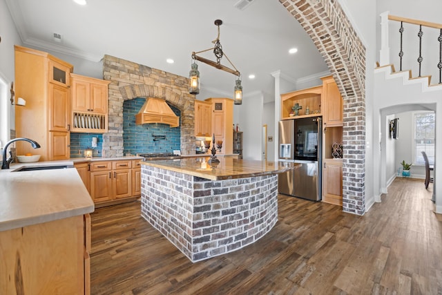 kitchen featuring premium range hood, a center island, sink, light brown cabinets, and stainless steel fridge