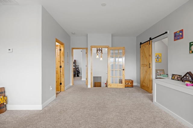 interior space with light carpet and a barn door