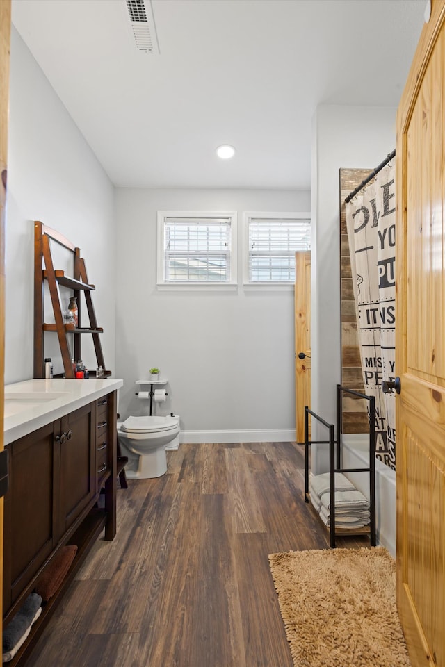 bathroom featuring toilet, walk in shower, hardwood / wood-style floors, and vanity